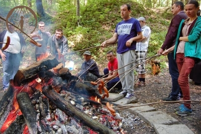 Uczestnicy spotkania pieką kiełbaski nad ogniskiem