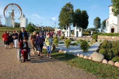 Grupa pielgrzymów, w tle Sanktuarium Matki Bożej Bolesnej, dzwonnica oraz Góra Krzyży