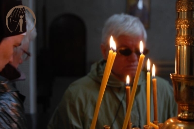 Wnętrze Prawosławnego Monastyru Zwiastowania Przenajświętszej Bogurodzicy w Supraślu, zapalone świece wotywne w tle twarze pań