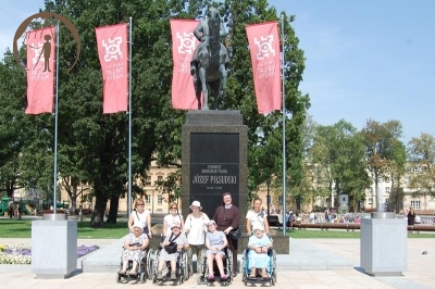 Mieszkanki i przewodnicy przed pomnikiem Józefa Piłsudskiego, w tle budynek UMCS-u przy Placu Litewskim