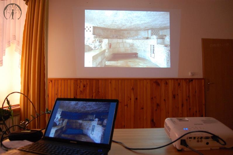 Świetlica w Domu Nadziei, pierwszy plan laptop i projektor stoją na blacie stołu, drugi plan fotografia z Ziemi Świętej wyświetlona na ścianie