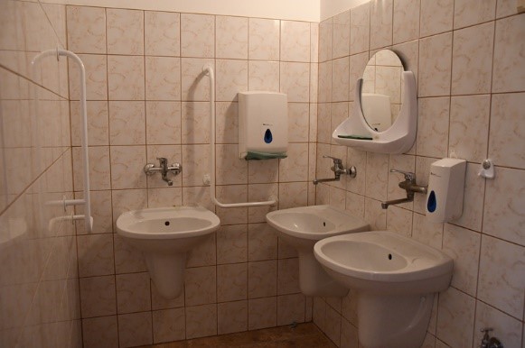 Łazienka w budynku Dom Nadziei, trzy umywalki, przy dwóch umywalkach poręcze