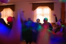 Świetlica Domu Nadziei, Bal Sylwestrowy, Mieszkanki i Uczestnicy WTZ stojąc w okręgu podnoszą i opuszczają kolorową okrągłą chustę animacyjną na której znajdują się balony