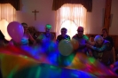 Świetlica Domu Nadziei, Bal Sylwestrowy, Mieszkanki i Uczestnicy WTZ stojąc w okręgu podnoszą i opuszczają kolorową okrągłą chustę animacyjną na której znajdują się balony