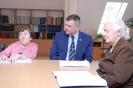 Soli Deo, czytelnia,  Wicewojewoda Lubelski Pan Robert Gmitruczuk siedzi przy stole z Panią Teresą i Panią Joanną czytającą książkę zapisaną alfabetem braille`a